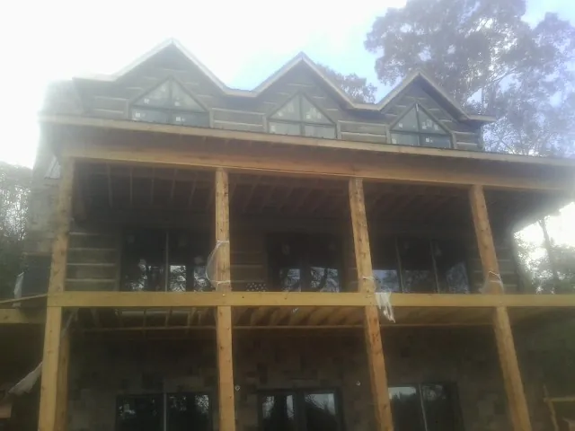 Dormers and porch framing on a large log home under construction — Roof Coating work by our crew in West Bloomfield
