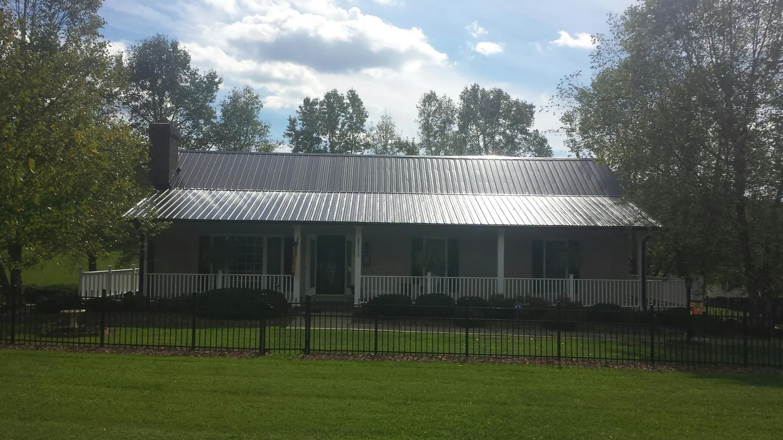 Gray metal roof on a brick ranch with a full width front porch — Gutter Guard Installation work by our crew in West Bloomfield