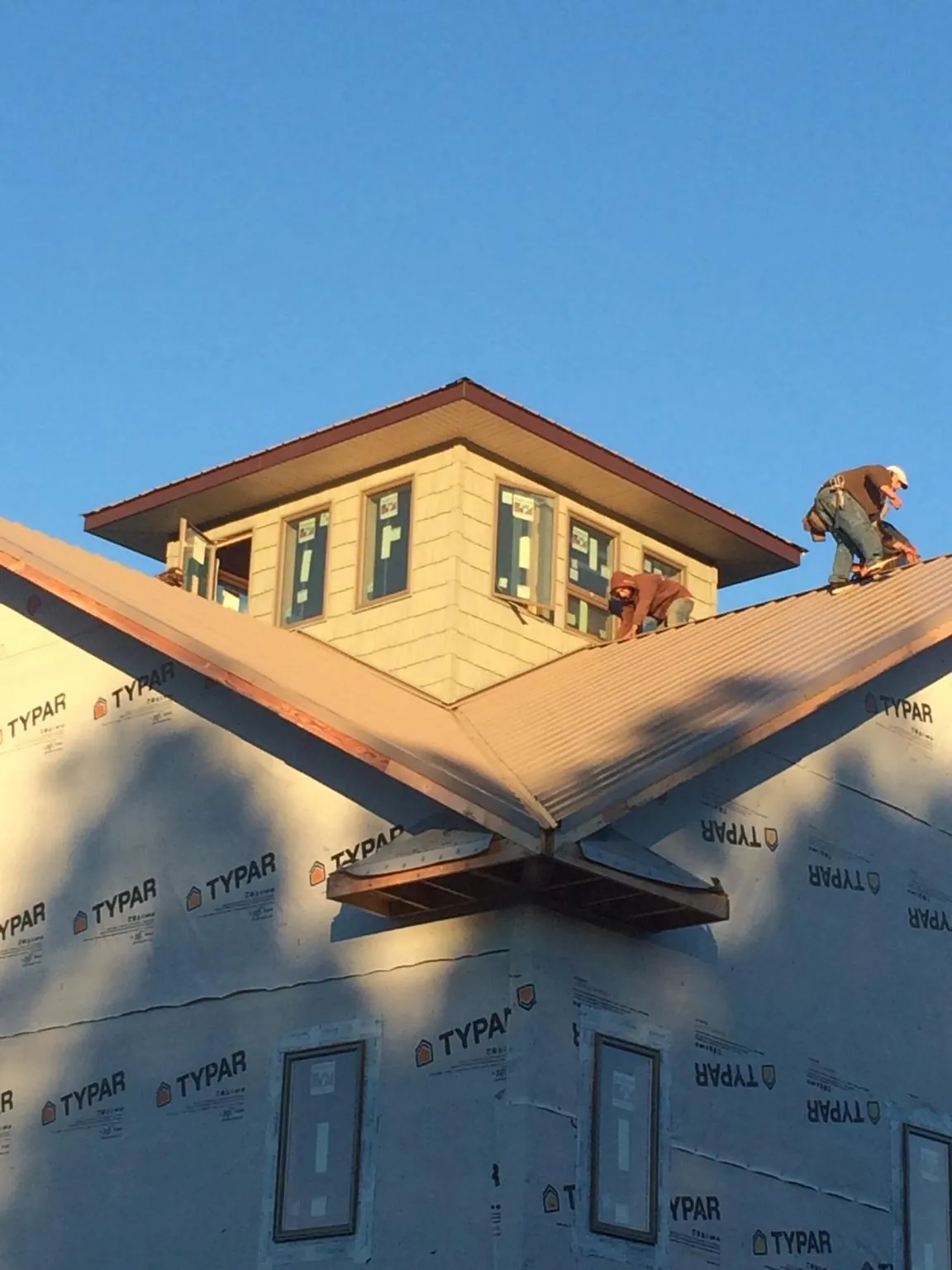 Roofers working around a rooftop cupola on a new metal roof at sunset — Roof Waterproofing in West Bloomfield by Roofing Brothers